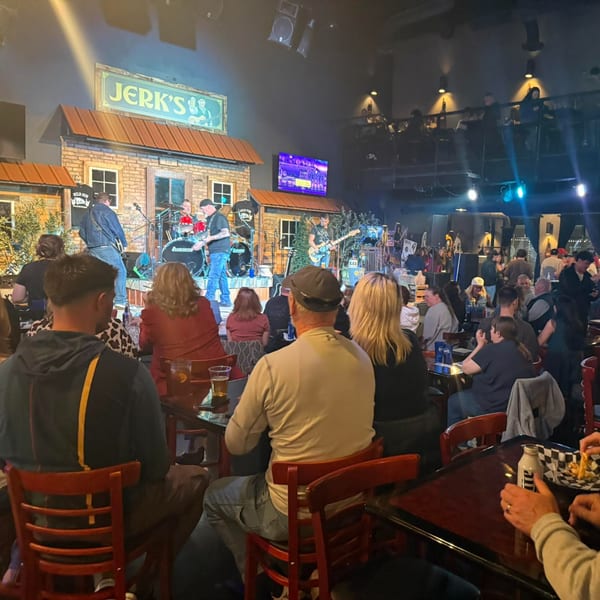 A band performs on stage at Jerk's restaurant, with patrons seated at tables watching.